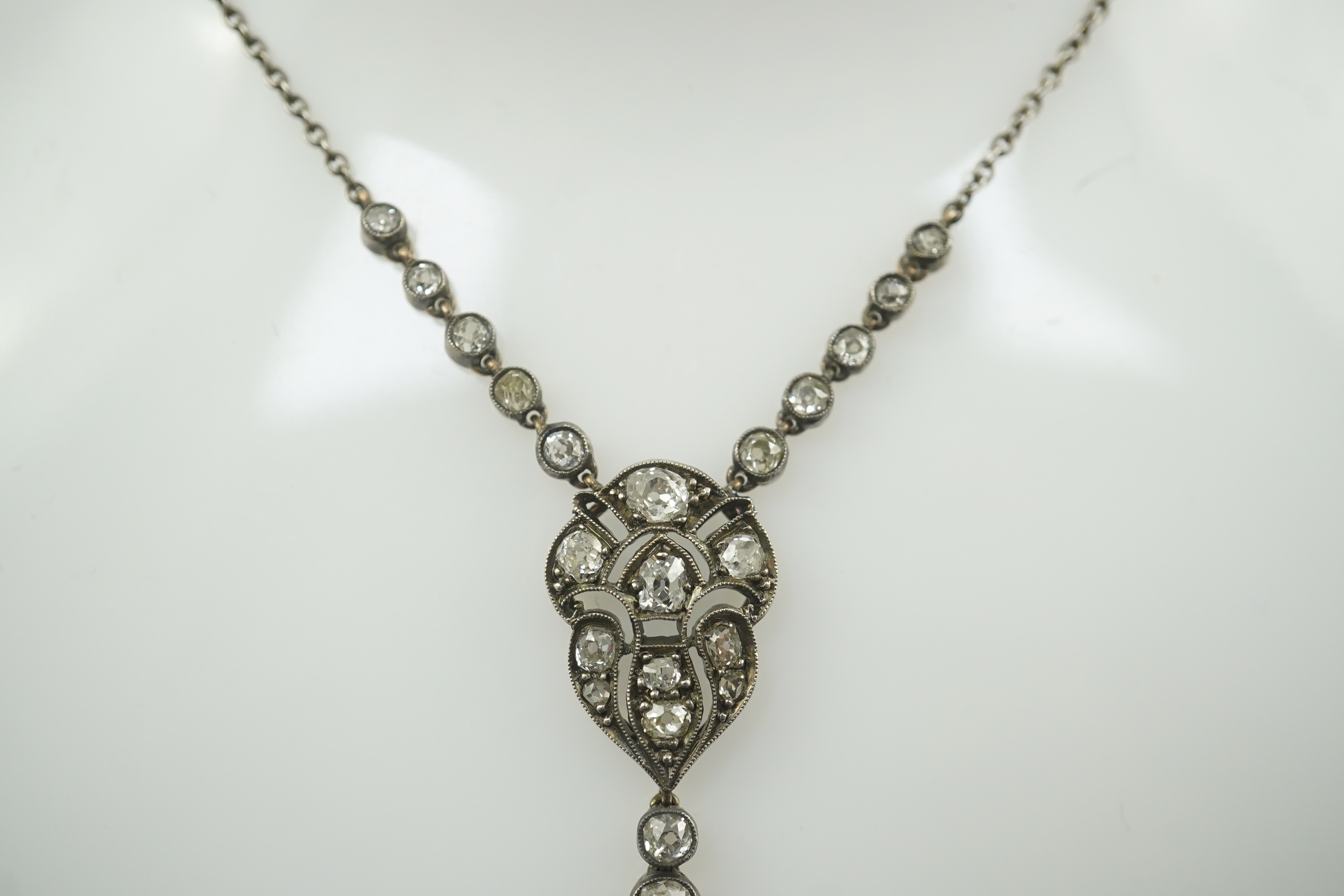 A Belle Epoque gold and silver, millegrain set sapphire and diamond cluster set drop pendant necklace